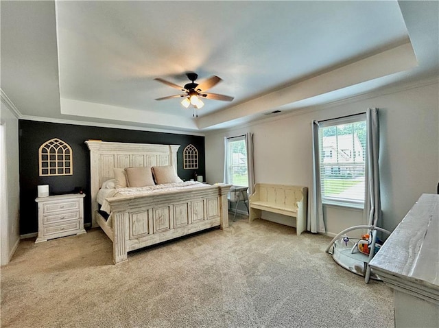 bedroom featuring a tray ceiling, multiple windows, light colored carpet, and ornamental molding