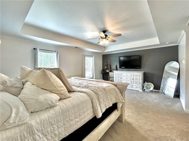 carpeted bedroom featuring a raised ceiling, crown molding, baseboards, and a ceiling fan