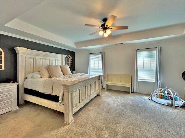 bedroom with a tray ceiling, light carpet, and a ceiling fan