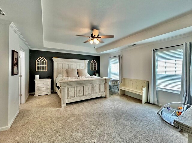 bedroom with a raised ceiling, light colored carpet, crown molding, ceiling fan, and baseboards