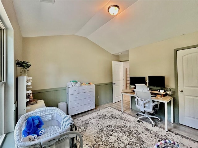 office space featuring a wainscoted wall, lofted ceiling, and wood finished floors