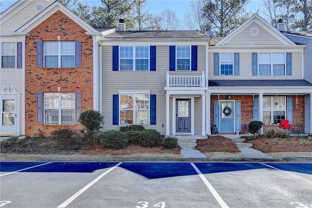 townhome / multi-family property featuring a chimney, uncovered parking, and brick siding