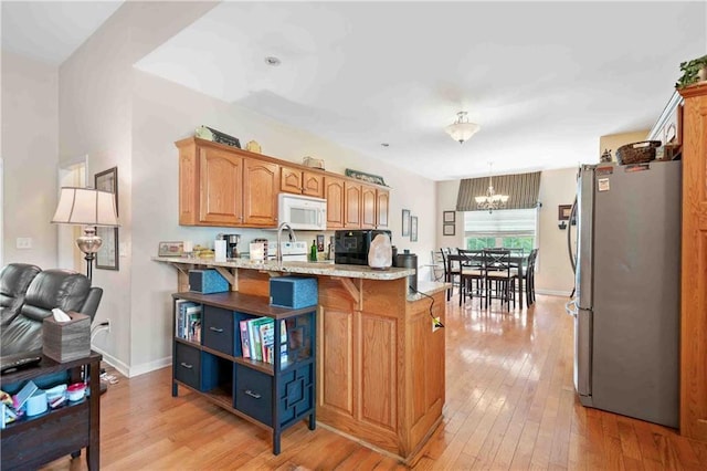 250 Brianna Blvd, Calhoun, GA 30701 - kitchen featuring freestanding refrigerator, white microwave, light wood-style flooring, a chandelier, and a kitchen bar