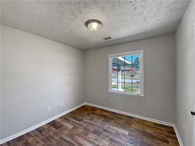 unfurnished room with a textured ceiling and dark hardwood / wood-style floors