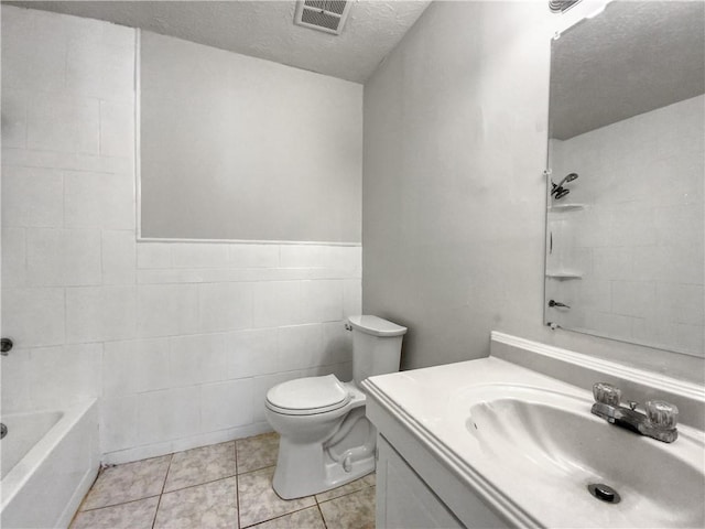 full bathroom with vanity, tile patterned flooring, toilet, a textured ceiling, and tile walls