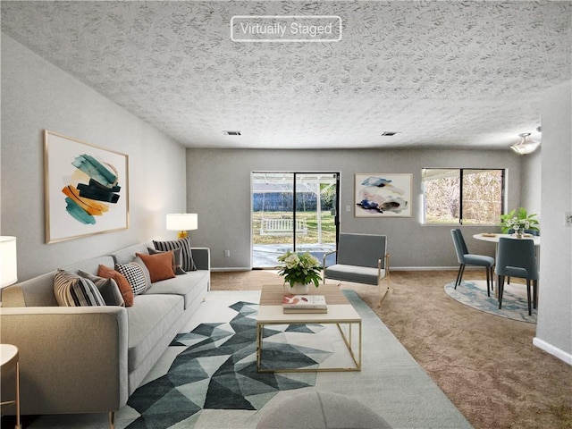 living room featuring carpet, a textured ceiling, and a wealth of natural light