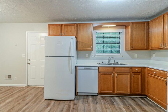 2045 Scarbrough Dr, Stone Mountain, GA 30088 - kitchen with white appliances, a sink, light wood-style floors, brown cabinetry, and a textured ceiling
