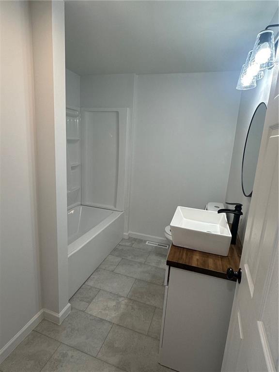 full bathroom featuring tile patterned flooring, vanity, toilet, and  shower combination