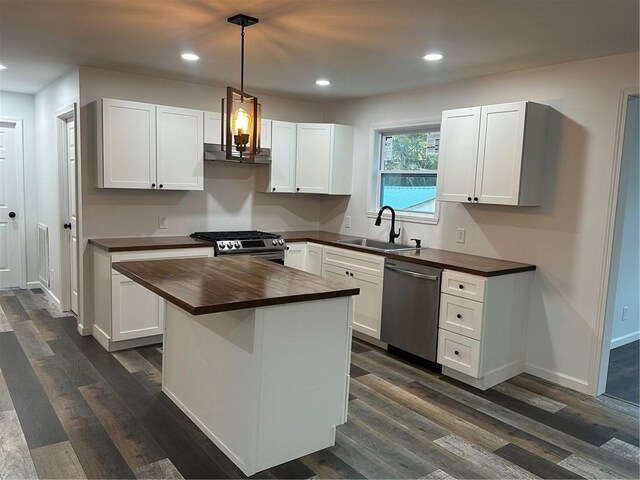 kitchen with white cabinetry, sink, dark wood-type flooring, stainless steel appliances, and a kitchen island