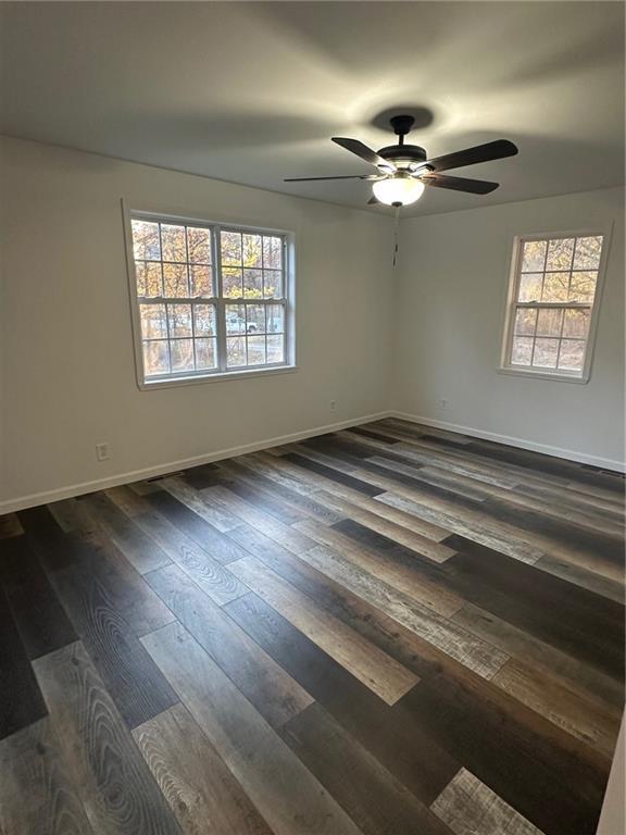 spare room with dark hardwood / wood-style floors and ceiling fan