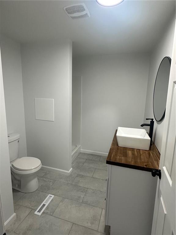 bathroom with a shower, vanity, and toilet