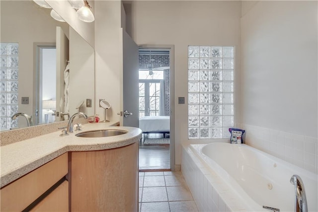 bathroom with tile patterned flooring, vanity, and tiled tub