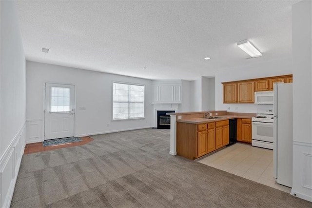 kitchen featuring sink, light carpet, kitchen peninsula, and white appliances