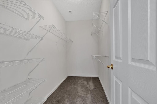 walk in closet featuring dark colored carpet