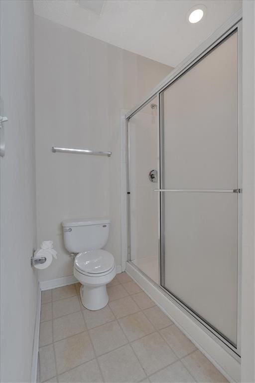 bathroom with tile patterned flooring, a shower with door, and toilet