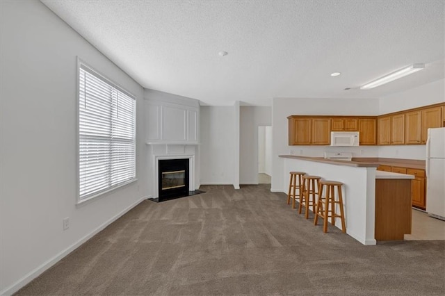 kitchen featuring a kitchen breakfast bar, white appliances, kitchen peninsula, and light carpet