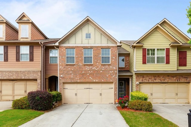 townhome / multi-family property featuring an attached garage, board and batten siding, brick siding, and driveway