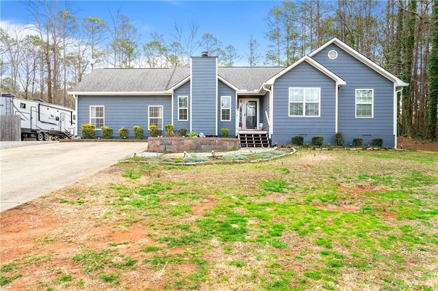 ranch-style house featuring a shingled roof, concrete driveway, a chimney, crawl space, and a front yard