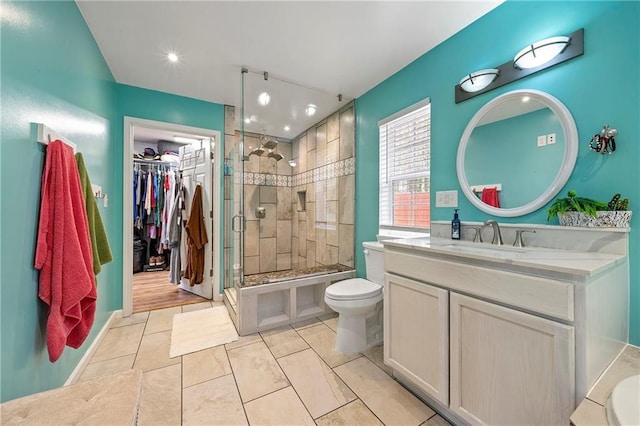 full bathroom featuring toilet, a shower stall, vanity, and a walk in closet