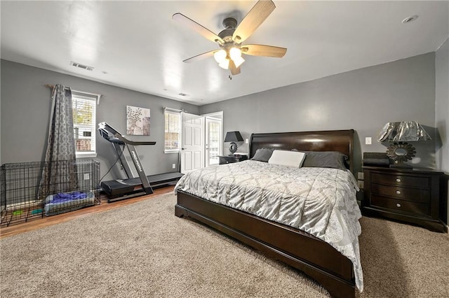 bedroom with a ceiling fan, visible vents, and wood finished floors