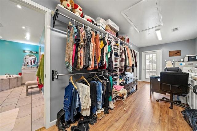 walk in closet featuring visible vents, wood finished floors, and attic access