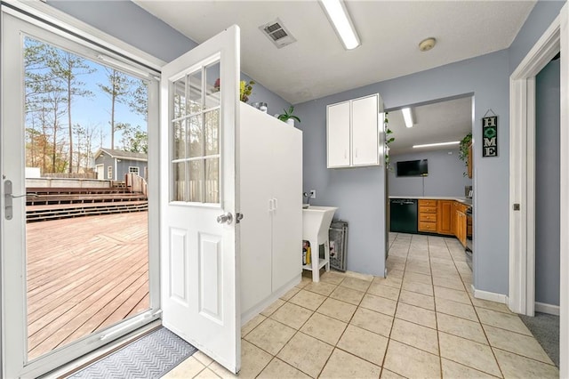 kitchen with black dishwasher, light tile patterned floors, plenty of natural light, and visible vents