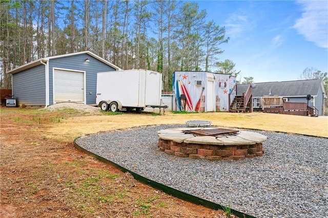 view of yard with a garage, a fire pit, and an outbuilding