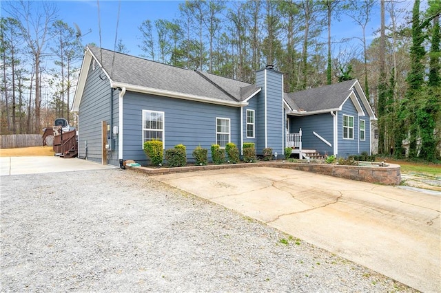 single story home featuring driveway, a chimney, and roof with shingles