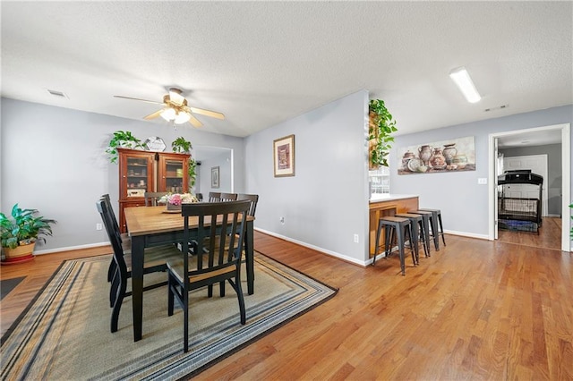 dining area with a textured ceiling, wood finished floors, and visible vents