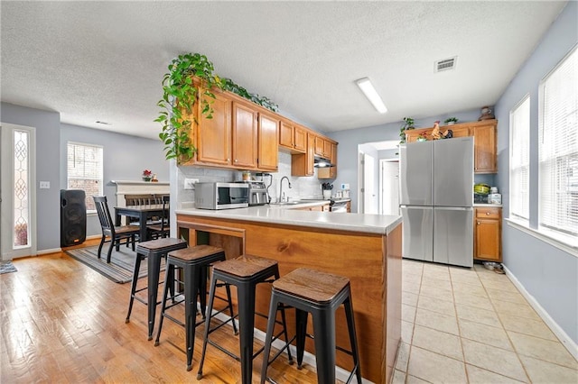 kitchen featuring stainless steel appliances, tasteful backsplash, light countertops, visible vents, and a peninsula