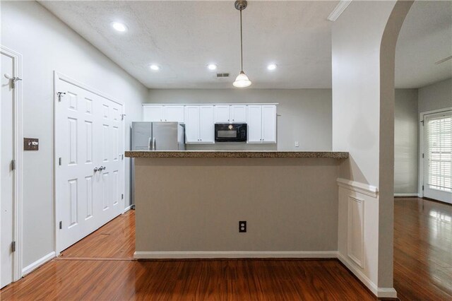 4844 W Park Cir Unit 4844, College Park, GA 30349 - kitchen with black microwave, freestanding refrigerator, wood finished floors, white cabinets, and a peninsula