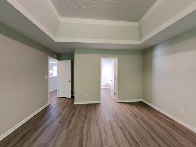 unfurnished room with baseboards, a raised ceiling, and dark wood-style floors