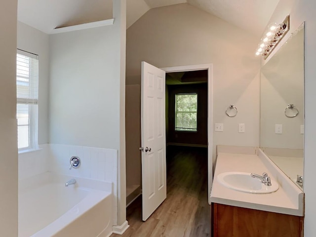 full bathroom with vanity, wood finished floors, a bath, and vaulted ceiling