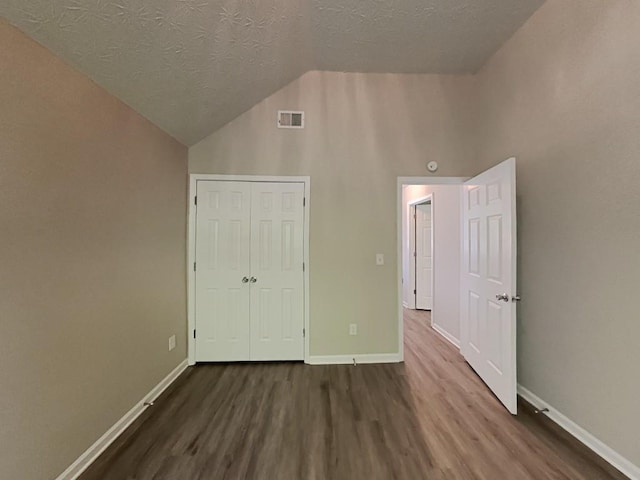 unfurnished bedroom with a textured ceiling, baseboards, visible vents, and wood finished floors