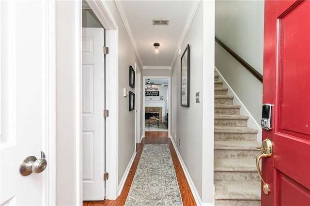 hallway with wood-type flooring and ornamental molding