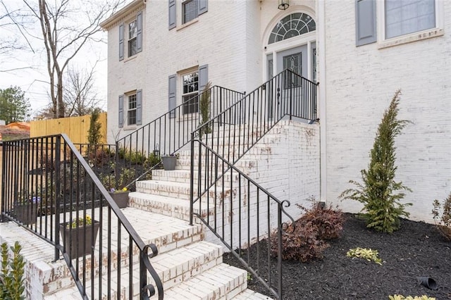 view of exterior entry with brick siding and fence