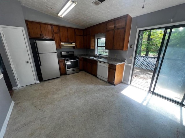 kitchen with stainless steel gas range, dishwasher, freestanding refrigerator, a sink, and vaulted ceiling