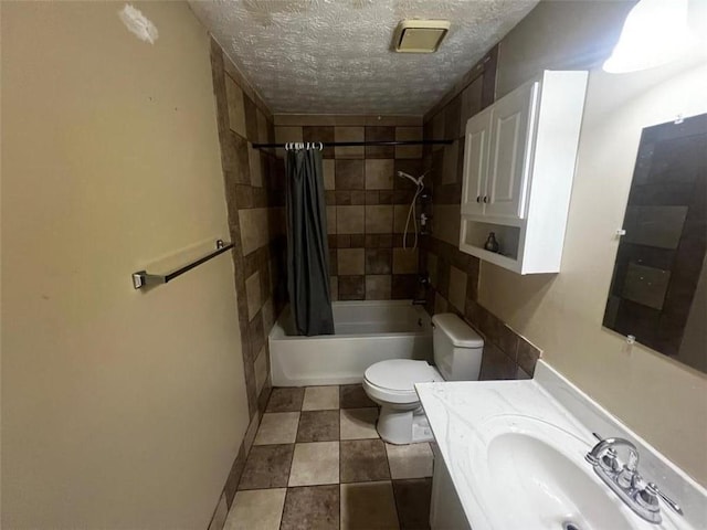bathroom featuring toilet, a textured ceiling, shower / bath combo with shower curtain, and vanity