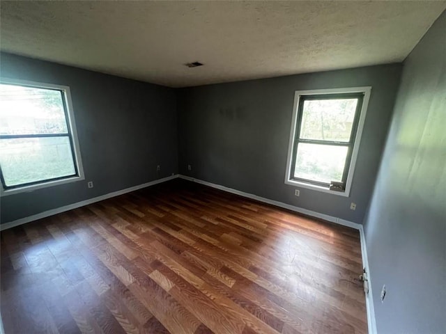 empty room featuring dark wood finished floors, baseboards, and a textured ceiling
