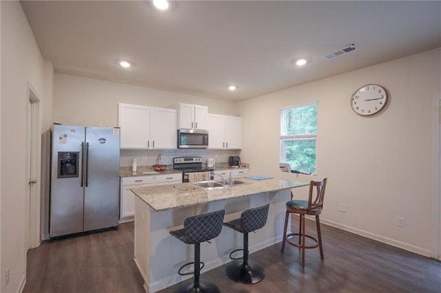 357 Hughes Ln, Pendergrass, GA 30567 - kitchen with appliances with stainless steel finishes, white cabinetry, a breakfast bar area, dark wood-style flooring, and decorative backsplash