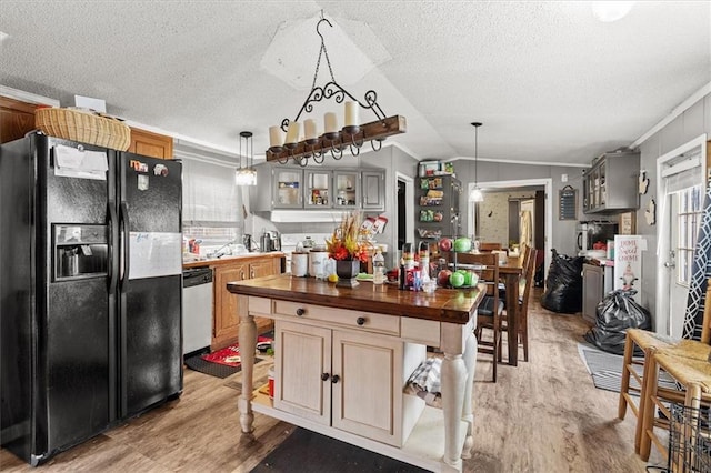 kitchen with butcher block countertops, light wood-style flooring, black fridge, stainless steel dishwasher, and lofted ceiling