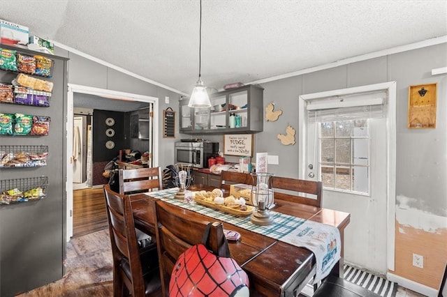 dining room featuring ornamental molding, a textured ceiling, and vaulted ceiling