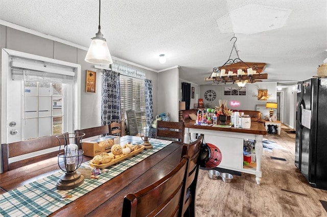 dining area with a textured ceiling, crown molding, and wood finished floors