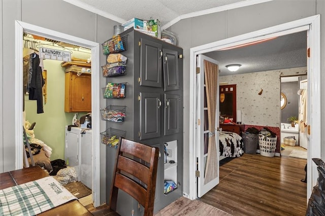 interior space featuring wood finished floors, lofted ceiling, ornamental molding, a textured ceiling, and washing machine and dryer