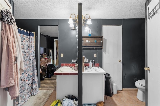 bathroom with vanity, toilet, and a textured ceiling