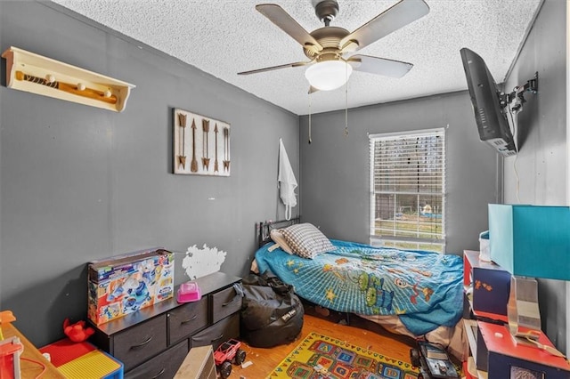 bedroom featuring ceiling fan, wood finished floors, and a textured ceiling