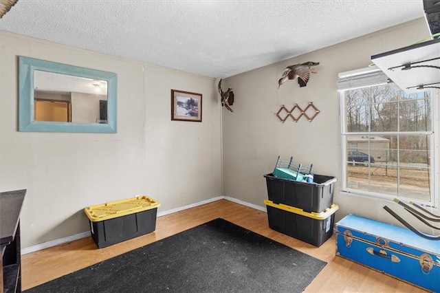 playroom featuring a textured ceiling, baseboards, and wood finished floors