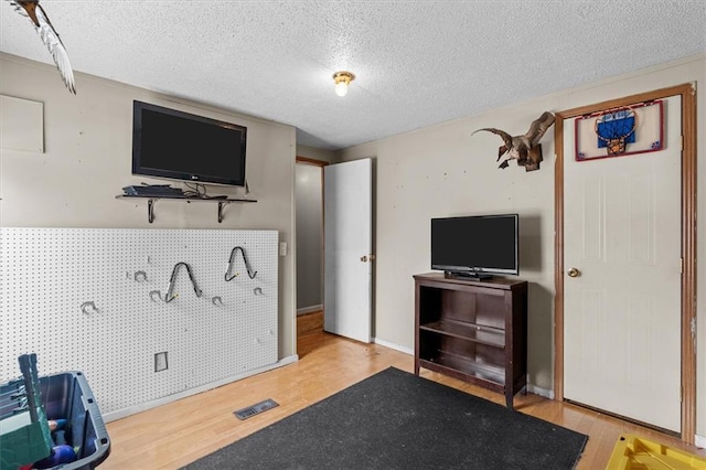 workout room with visible vents, a textured ceiling, and wood finished floors