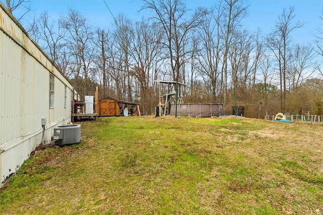 view of yard with an outdoor pool, an outbuilding, a storage shed, and central AC