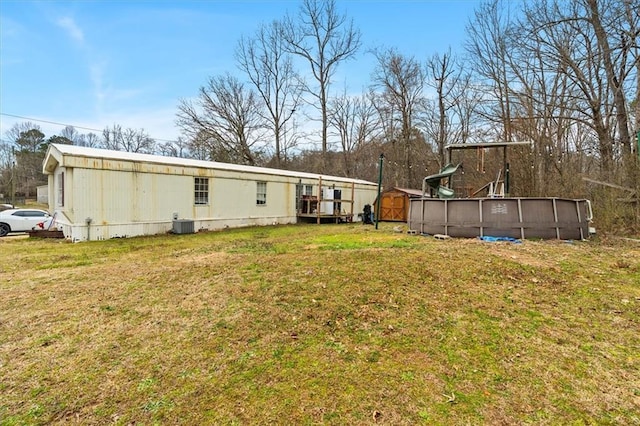 view of yard featuring an outdoor pool, a storage unit, and an outbuilding